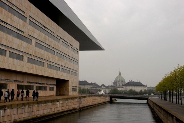 Das Opernhaus (Vordergrund), der Königspalast Amalienborg (Mitte) und die St. Fredericks Kirche (Barocker Kuppelbau im Hintergrund) bilden die K-K-K Achse Kopenhagens, die das Gleichgewicht zwischen Kultur, Königshaus (Politik) und Kirche (Religion), darstellt.