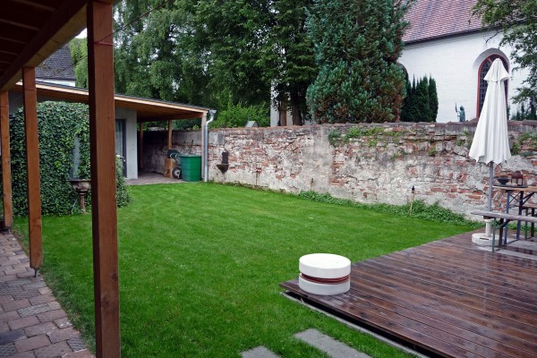 Atriumgarten mit alter Friedhofsmauer, Holzterrasse und hist. Efeu